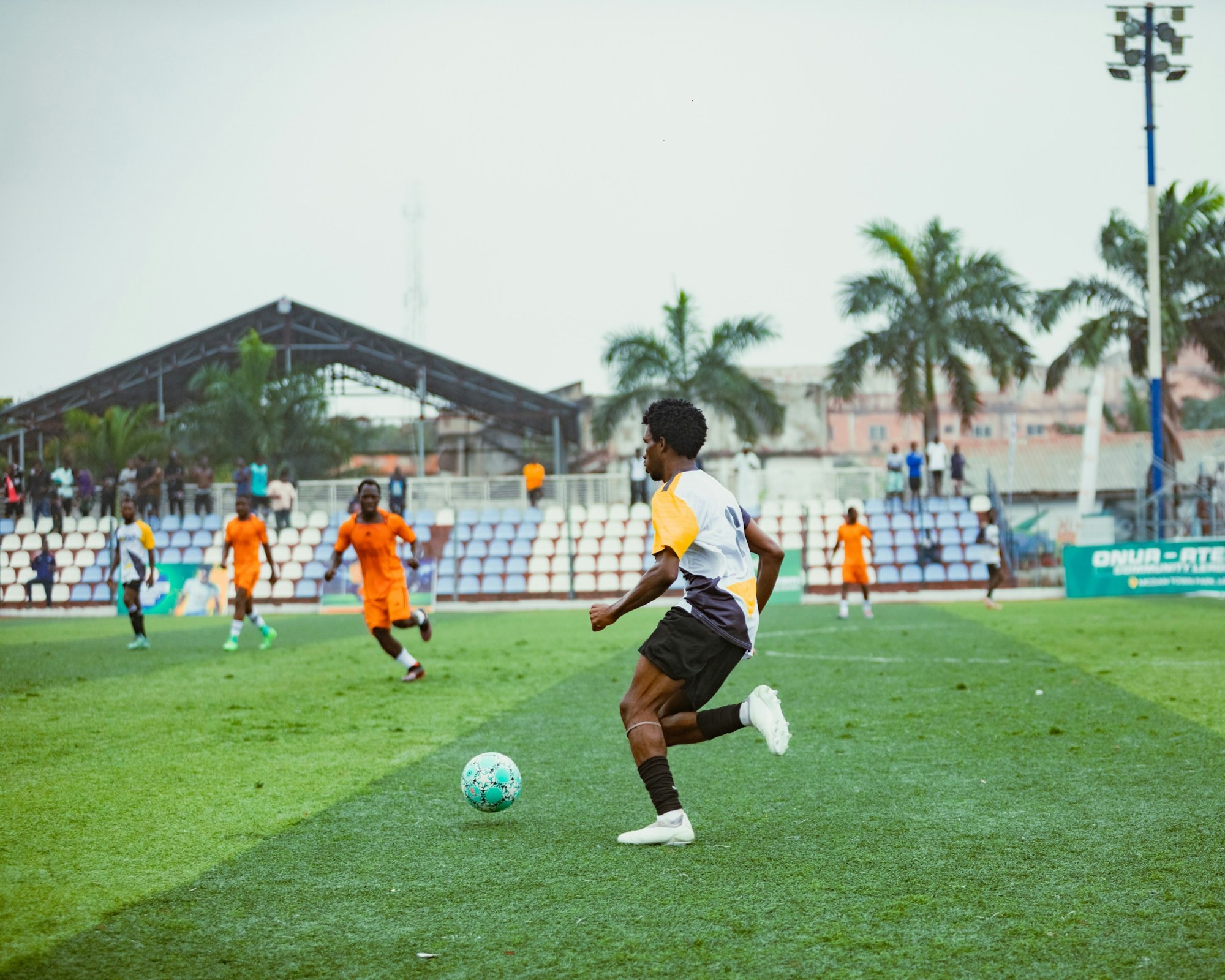 A player carrying the ball forward in a small stand-side stadium
